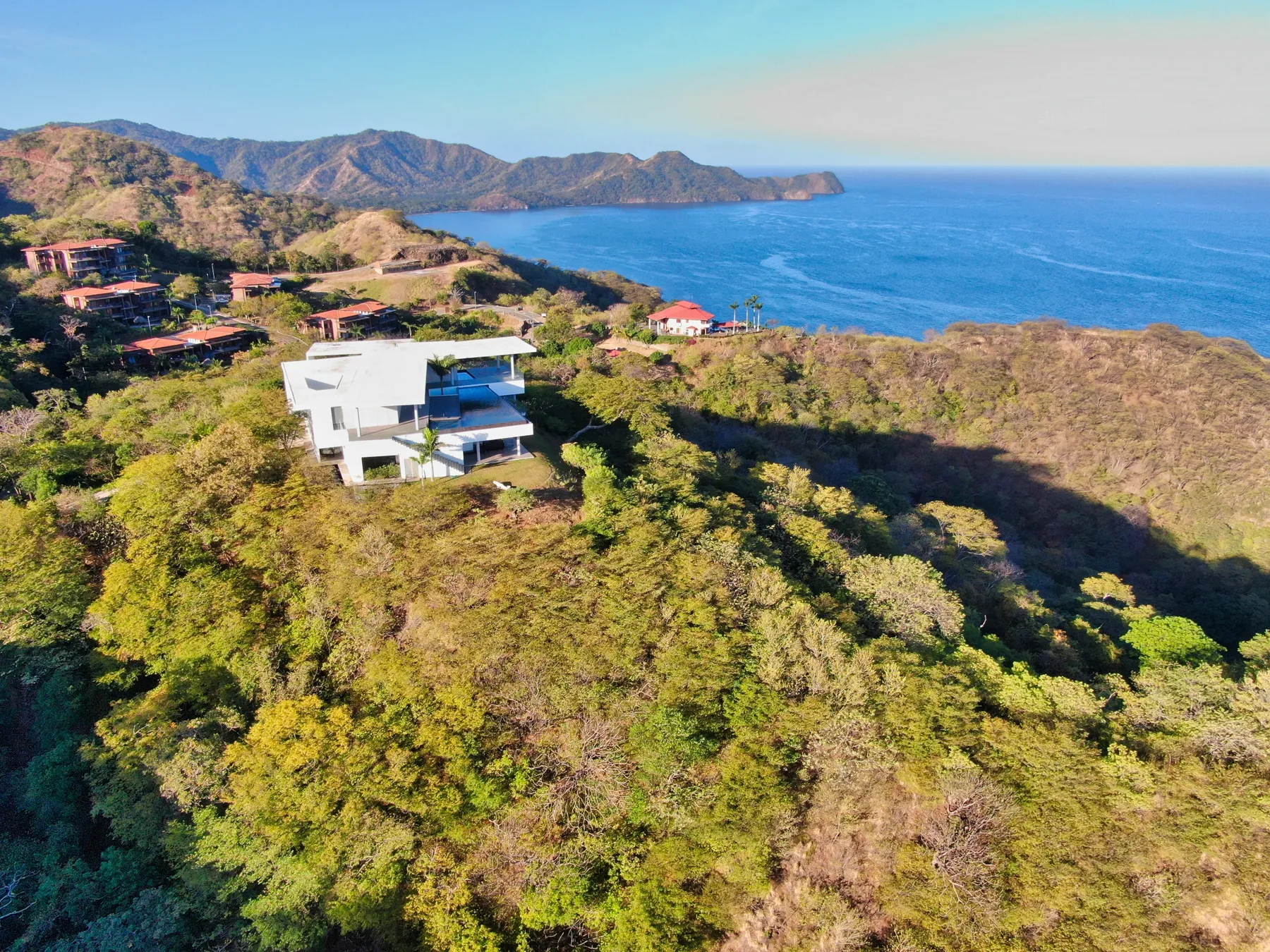 Dry forested hills above the Pacific in Guanacaste, with houses on the ridge and a headland offshore